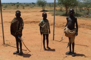 Ugandan children wearing their native shawls while holding sticks
