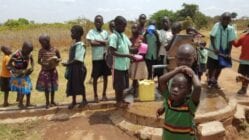 Ugandan children collecting water from an artesian well pump